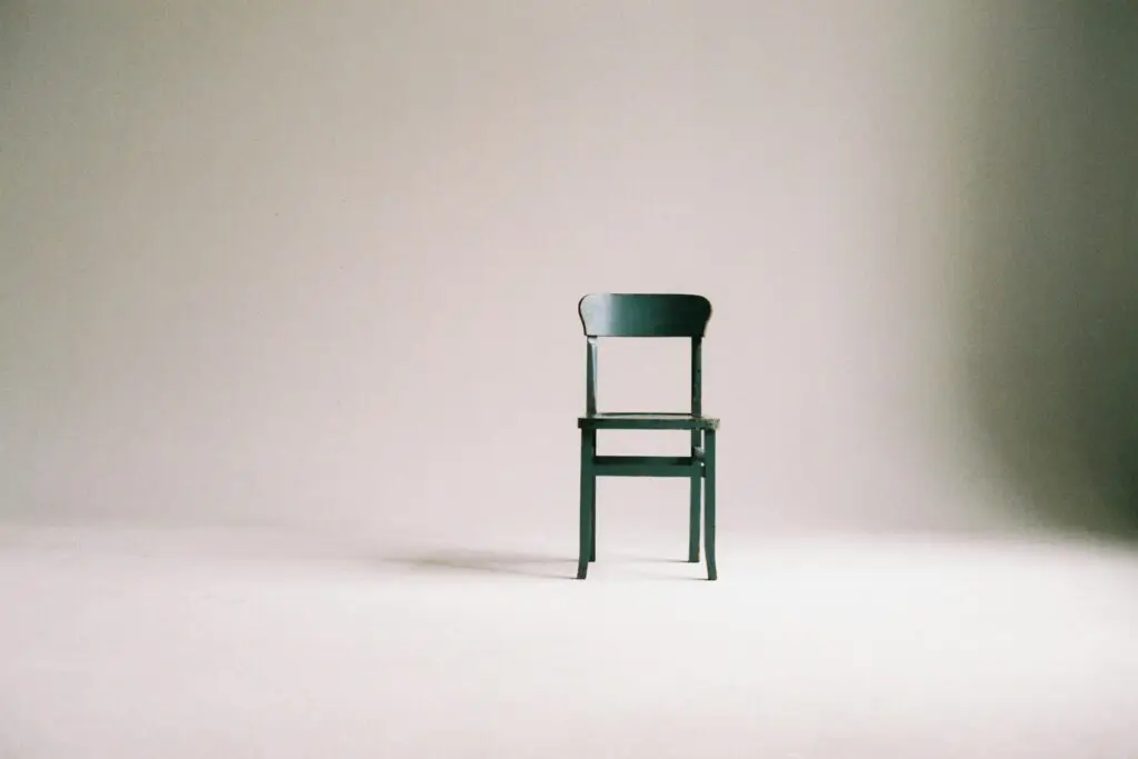 A single black chair in a minimalistic studio setting with a neutral backdrop.